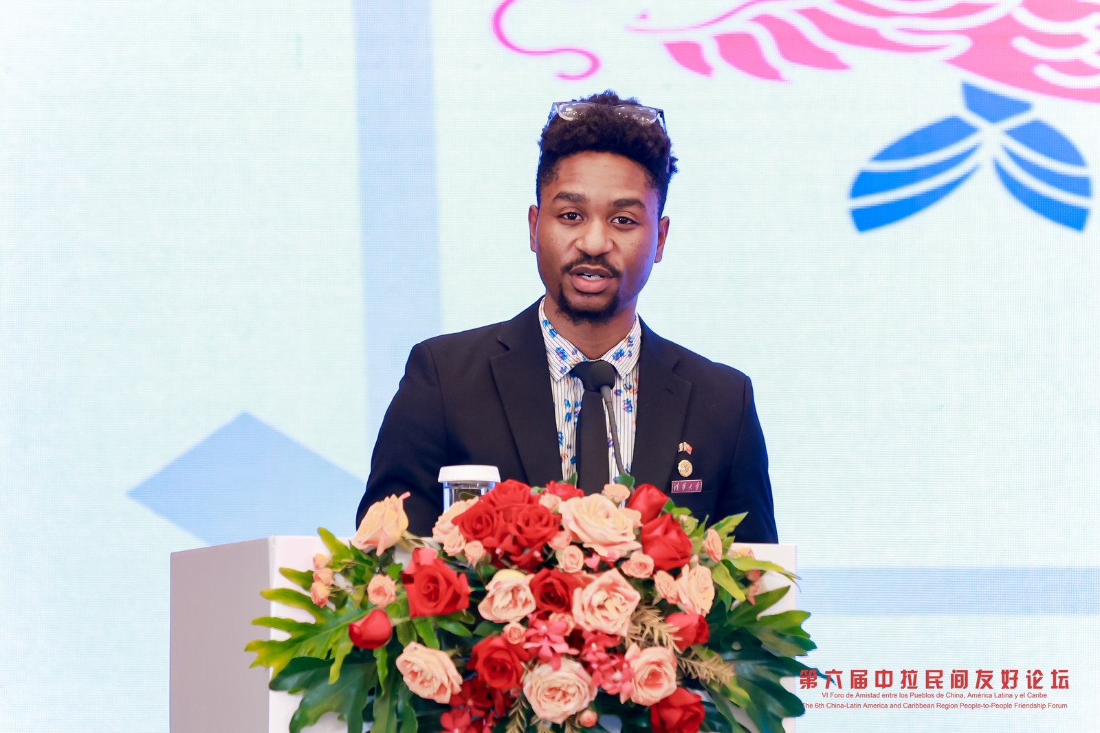 Joshua Johnson speaking from a podium at the China-Latin America and Caribbean friendship forum