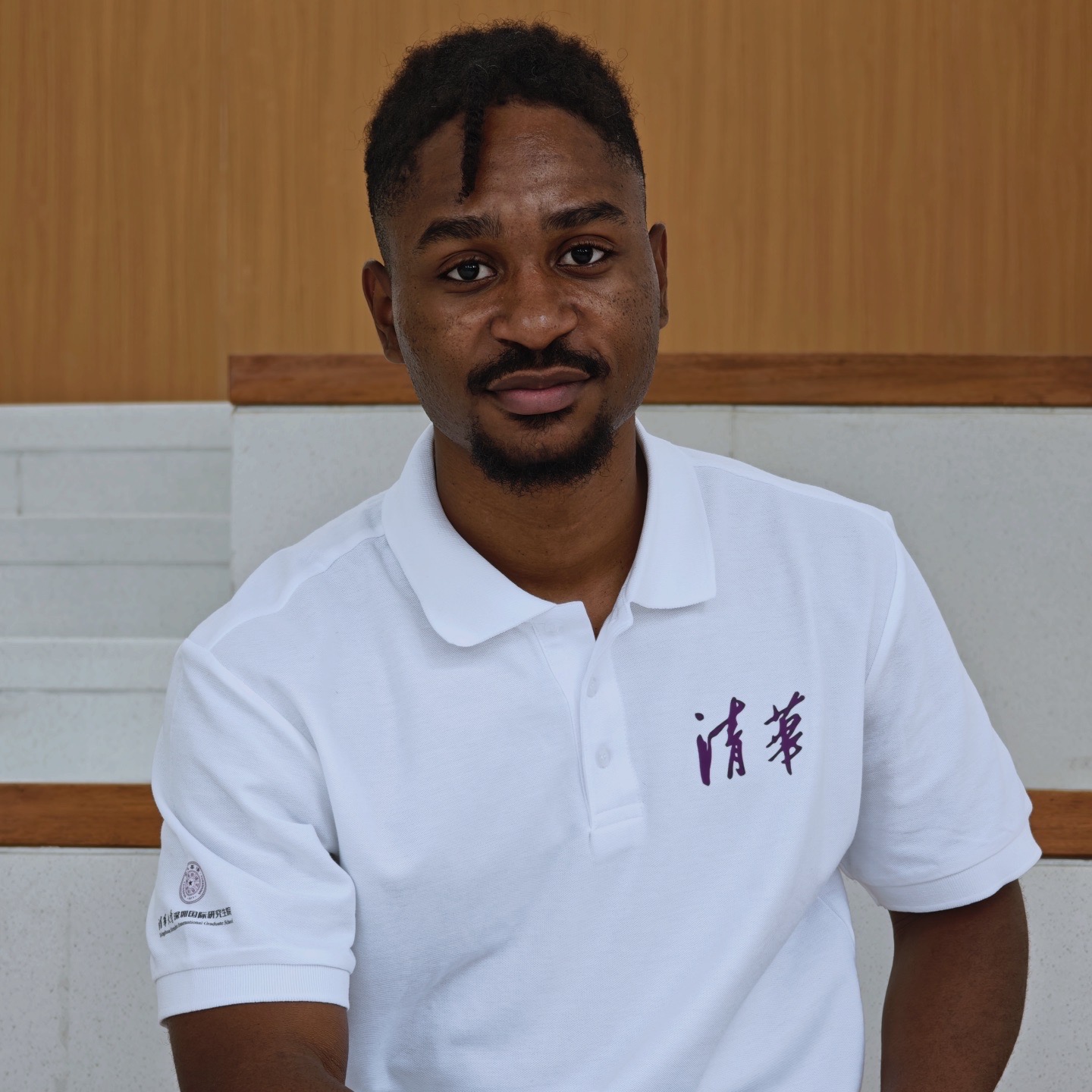 Joshua Johnson wearing a white Tsinghua shirt and looking directly at the camera